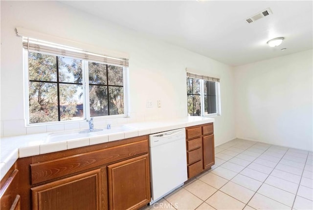 kitchen featuring tile counters, dishwasher, sink, and light tile patterned floors