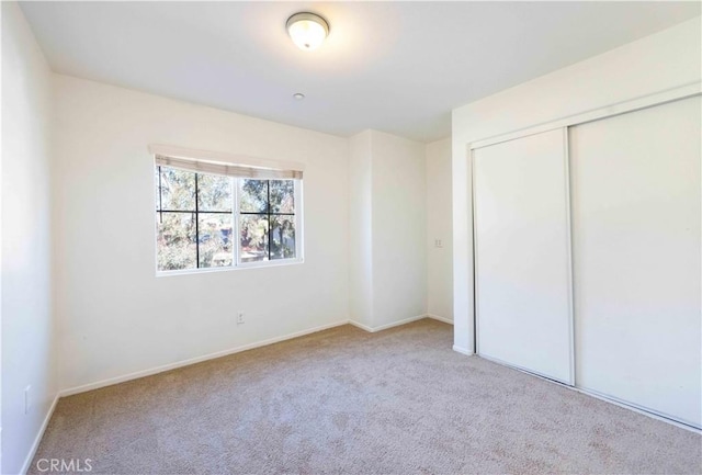 unfurnished bedroom featuring a closet and light carpet