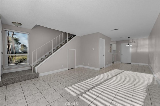 unfurnished living room with light tile patterned flooring and a textured ceiling