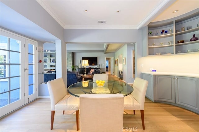 dining area with ornamental molding, french doors, and light wood-type flooring