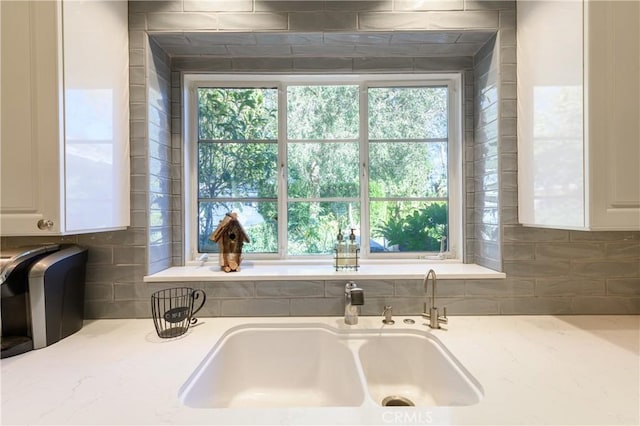 interior details with sink, white cabinets, and decorative backsplash