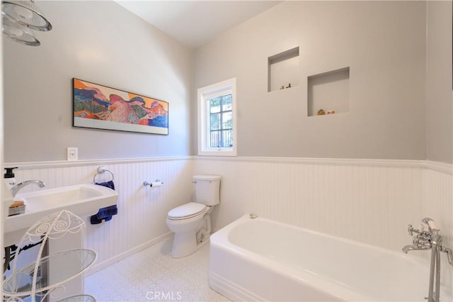 bathroom featuring a washtub, sink, and toilet