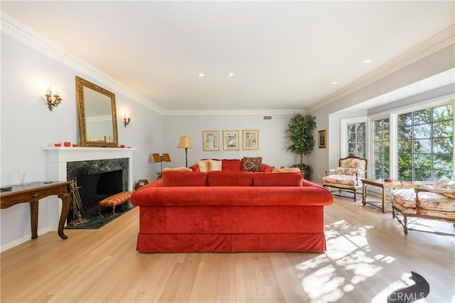 living room featuring ornamental molding, a high end fireplace, and light hardwood / wood-style flooring