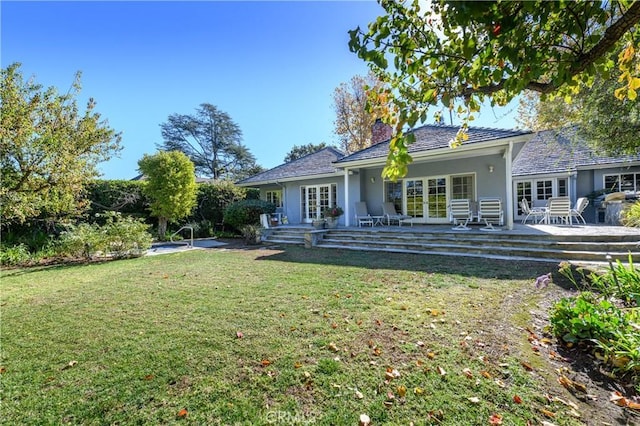 back of property with a patio, a lawn, and french doors