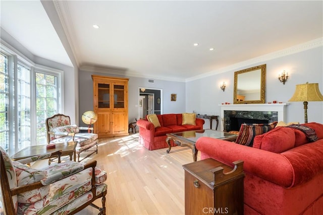 living room featuring ornamental molding, a high end fireplace, and light hardwood / wood-style flooring