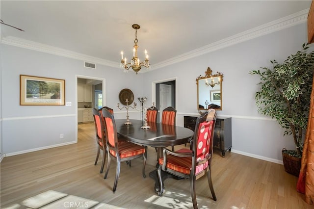 dining space with crown molding, light hardwood / wood-style floors, and a notable chandelier