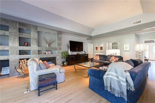 living room with a fireplace, light hardwood / wood-style floors, and vaulted ceiling