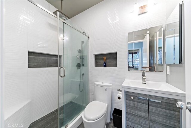 bathroom featuring vanity, a shower with shower door, tile walls, and toilet