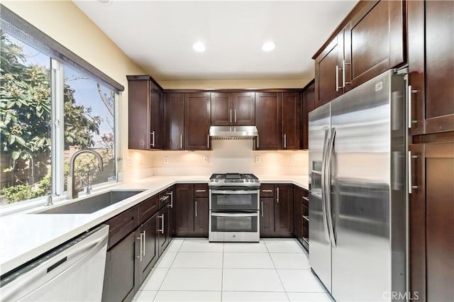 kitchen featuring stainless steel appliances, sink, light tile patterned floors, and dark brown cabinetry