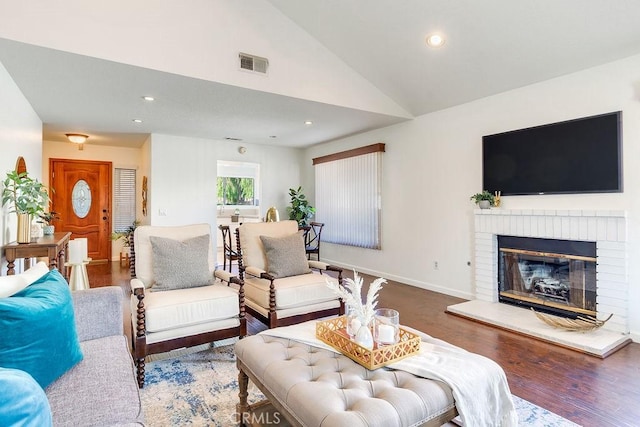 living room featuring a brick fireplace, hardwood / wood-style flooring, and high vaulted ceiling