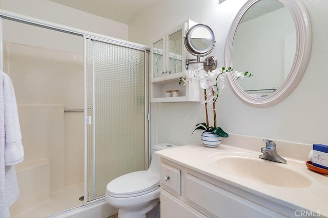 bathroom with a shower with door, vanity, and toilet