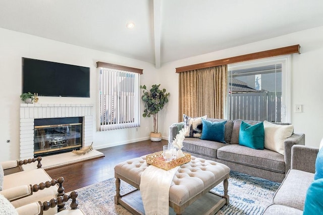 living room with lofted ceiling with beams, a healthy amount of sunlight, a fireplace, and hardwood / wood-style floors