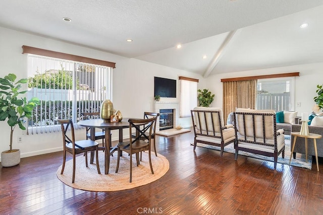 dining area with dark hardwood / wood-style floors, a fireplace, and vaulted ceiling with beams