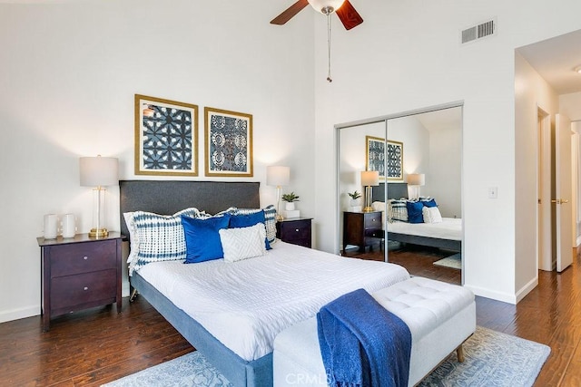 bedroom featuring dark hardwood / wood-style floors, a closet, ceiling fan, and a high ceiling