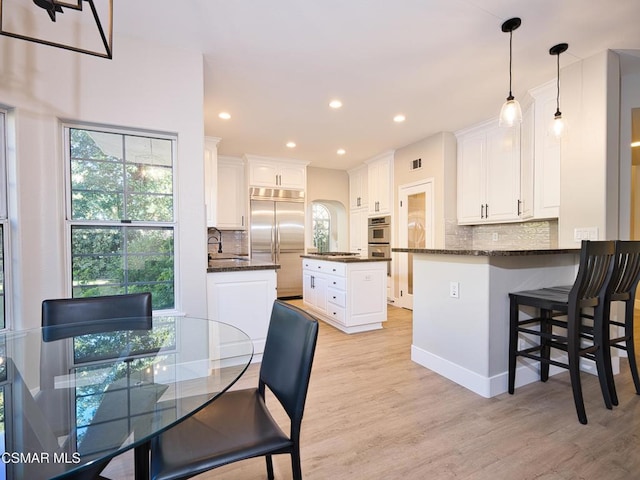 kitchen with pendant lighting, sink, appliances with stainless steel finishes, white cabinetry, and a kitchen island