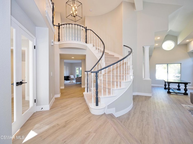 foyer entrance featuring french doors, a high ceiling, decorative columns, and light wood-type flooring