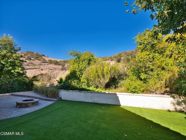 view of yard featuring a mountain view and an outdoor fire pit