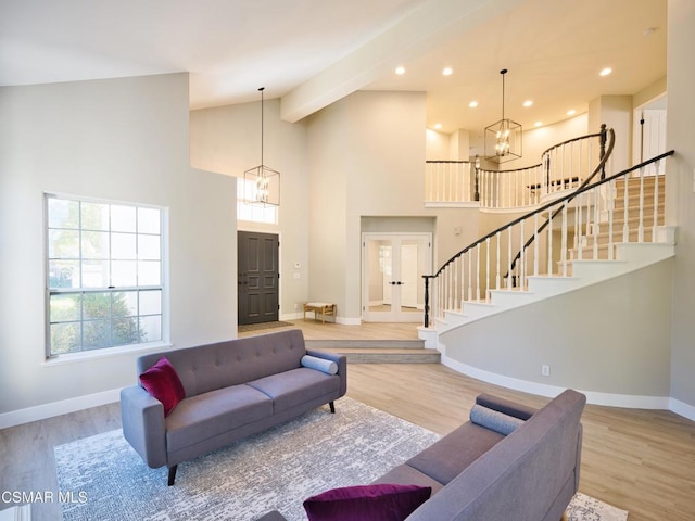 living room featuring high vaulted ceiling, light hardwood / wood-style flooring, and a notable chandelier