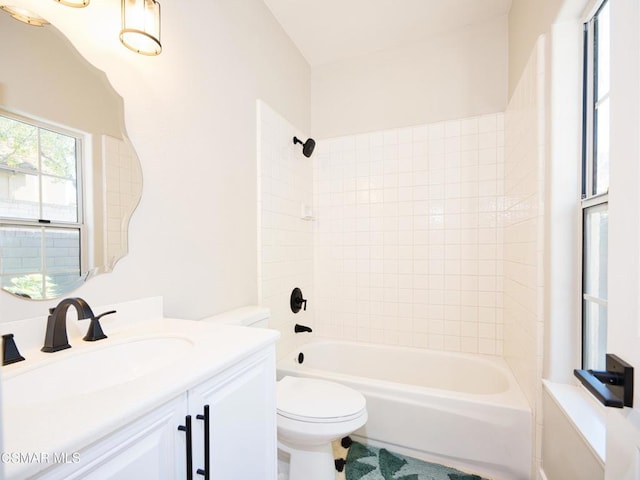 full bathroom featuring vanity, tiled shower / bath combo, and toilet