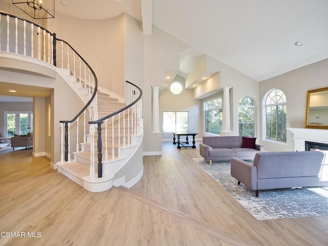 living room with wood-type flooring, high vaulted ceiling, and a healthy amount of sunlight