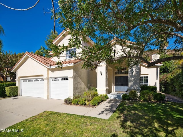 mediterranean / spanish home featuring a garage and a front yard