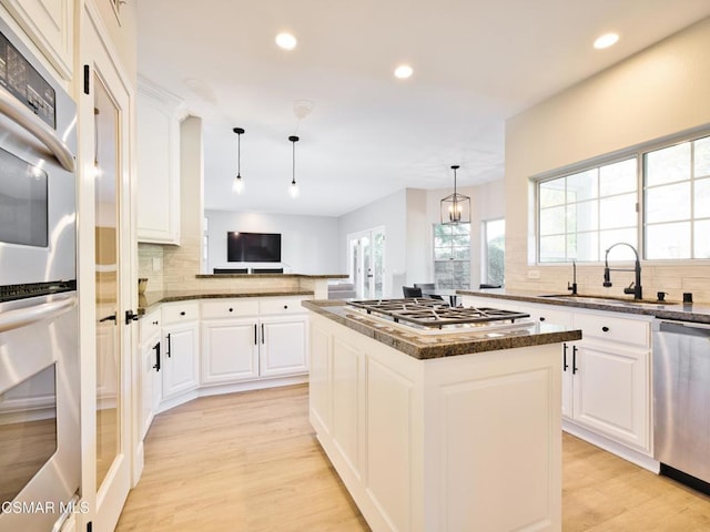 kitchen with a kitchen island, decorative light fixtures, sink, white cabinets, and stainless steel appliances