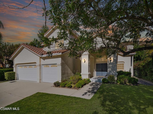 mediterranean / spanish-style home featuring a garage and a lawn