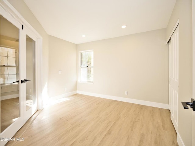 unfurnished bedroom with light hardwood / wood-style floors, a closet, and french doors