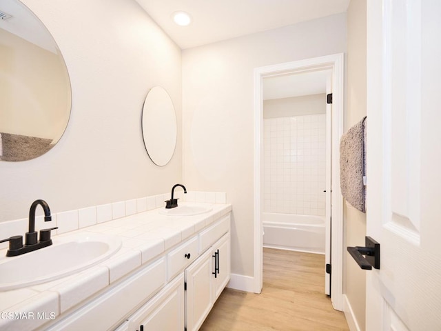 bathroom featuring vanity, wood-type flooring, and tiled shower / bath