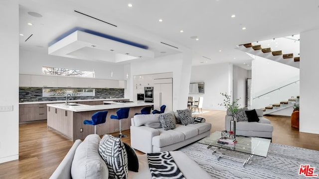 living room with light hardwood / wood-style floors, sink, and a high ceiling