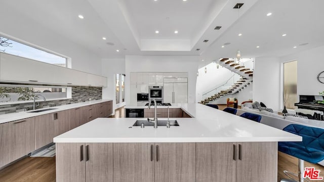 kitchen featuring a breakfast bar, sink, hardwood / wood-style flooring, paneled built in refrigerator, and a spacious island