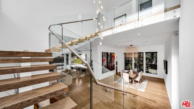 staircase with hardwood / wood-style flooring, a notable chandelier, and a high ceiling