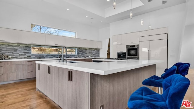 kitchen with a spacious island, sink, hanging light fixtures, appliances with stainless steel finishes, and a kitchen breakfast bar