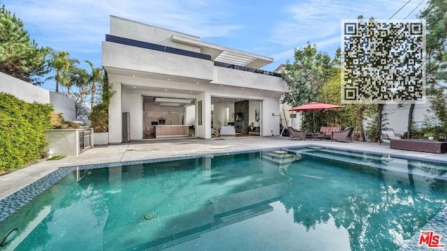 back of house featuring a fenced in pool, a patio, and an outdoor kitchen