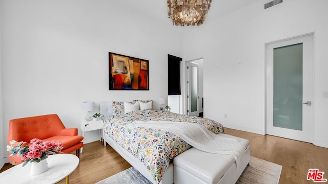 bedroom with an inviting chandelier and hardwood / wood-style floors