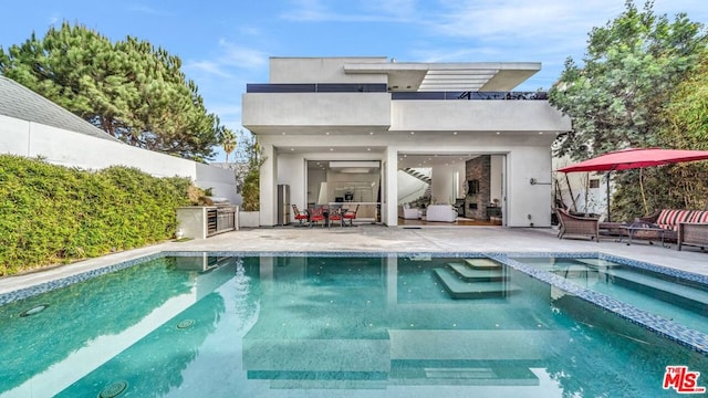 back of house featuring an outdoor kitchen, a pool with hot tub, and a patio area