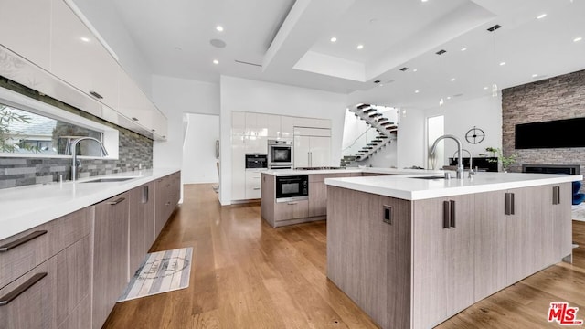 kitchen featuring built in appliances, sink, light hardwood / wood-style floors, and a spacious island