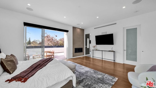 bedroom featuring access to outside, hardwood / wood-style floors, and a fireplace