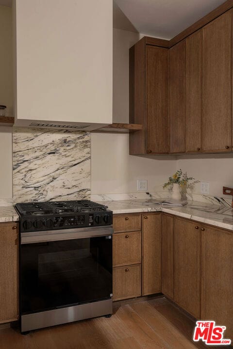 kitchen with black range with gas stovetop, dark wood-type flooring, and decorative backsplash