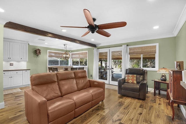 living room with beam ceiling, crown molding, french doors, and light wood-type flooring