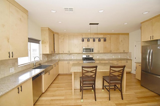 kitchen featuring sink, stainless steel appliances, a kitchen breakfast bar, a kitchen island, and light wood-type flooring