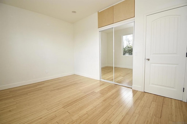 unfurnished bedroom with light wood-type flooring and a closet