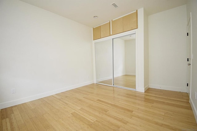 unfurnished bedroom with light wood-type flooring and a closet