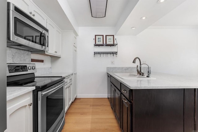 kitchen featuring dark brown cabinetry, sink, appliances with stainless steel finishes, light hardwood / wood-style floors, and white cabinets