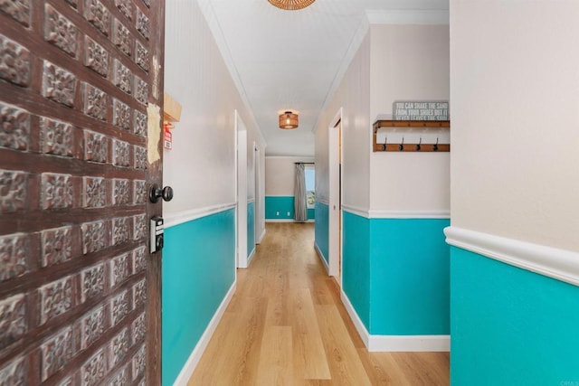 hall with ornamental molding and light hardwood / wood-style floors