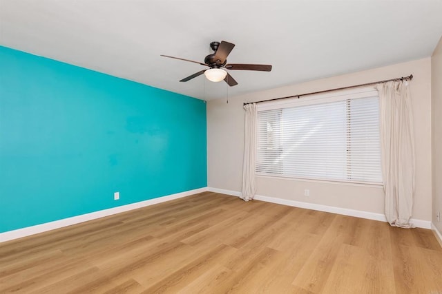 unfurnished room with light wood finished floors, baseboards, and a ceiling fan