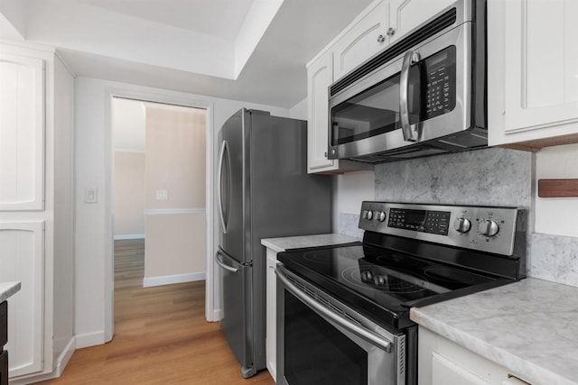 kitchen with white cabinets, stainless steel appliances, backsplash, and light countertops