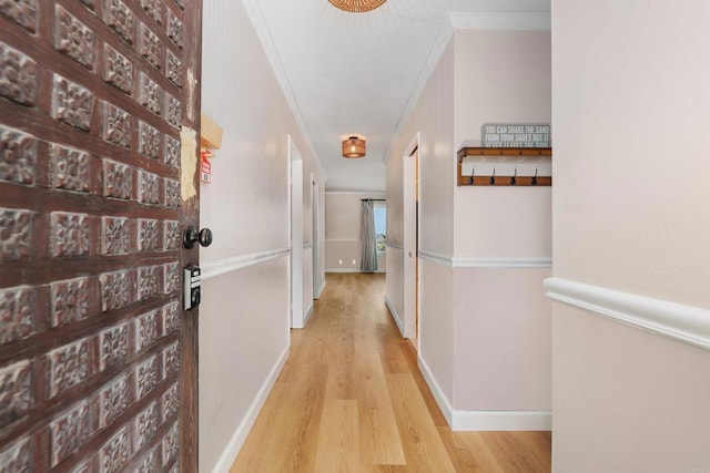 corridor featuring crown molding, baseboards, and wood finished floors