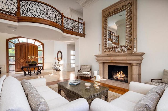 living room with hardwood / wood-style flooring, a towering ceiling, and a tiled fireplace