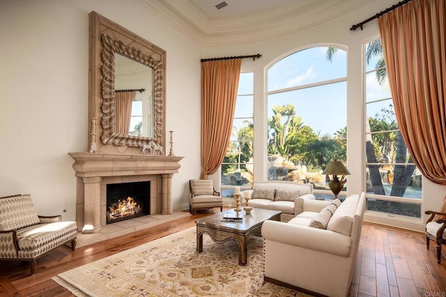 sitting room with a tiled fireplace, crown molding, and wood-type flooring